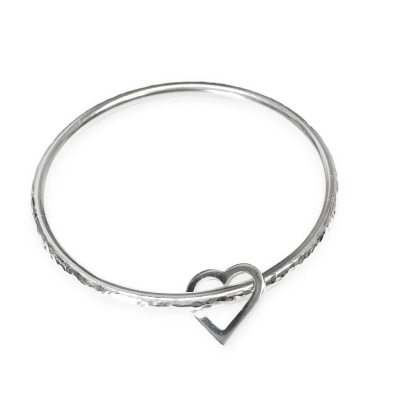 Sterling silver bangle with dimple texture and sterling silver heart charm. Available in 4 sizes.